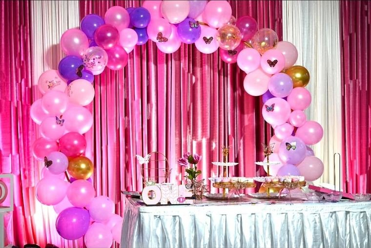 Pink and lilac butterfly balloon arch over a first birthday dessert table