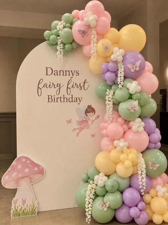 Fairy themed first birthday backdrop with a pastel balloon garland and butterfly accents