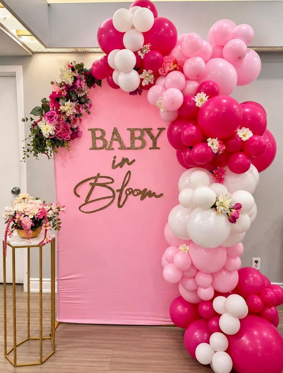 Hot pink Baby in Bloom baby shower backdrop with a pink and white balloon garland and gold lettering